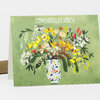 A greeting card with the word "CONGRATULATIONS!" in white at the top and an illustration of a colorful flower bouquet in a patterned vase on a green background.