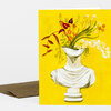 A greeting card featuring an illustration of a white bust vase filled with assorted flowers and foliage on a bright yellow front.