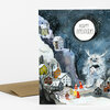 A folded holiday greeting card with an illustrated snowy village scene, a fluffy white creature holding a house, and the text "HAPPY HOLIDAYS" in a circular moon-like shape.