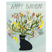 A greeting card with the text "HAPPY BIRTHDAY!" above an illustration of a black cat with a bouquet-like arrangement of cactus and flowers growing from its head.