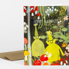 A folded greeting card with a colorful illustrated cover showing two smiling gnomes in a mushroom garden and the text "HAPPY BIRTHDAY!".