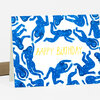 A folded greeting card with a pattern of blue star-covered figures and the words "HAPPY BIRTHDAY" in yellow on the front.