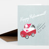 A folded greeting card with the words “Happy Retirement!” on the front and an illustration of a red car carrying a character in a pink headscarf, with “BEEP BEEP” beside it.