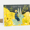A folded greeting card with the words "HAPPY TRAILS" and an illustration of a person riding a large pale rabbit in a yellow desert landscape with trees, flowers, and a starry sky.