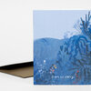 A folded greeting card with a blue illustrated landscape and the text "I am so sorry." on the front.