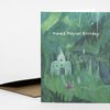 A folded birthday greeting card with a green magical forest scene, a small castle, a tiny figure in a red dress, and the text "Have a Magical Birthday!" on the front.