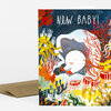 A folded greeting card with the text "NEW BABY!" and a colorful underwater illustration featuring a sleeping baby surrounded by coral and sea plants.