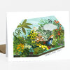 A folded greeting card shows a colorful illustrated greenhouse scene with flowers, potted plants, a cloud, and the text "SHOWERS BRING FLOWERS" on the front.