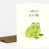 A folded greeting card with the text "SORRY TO BE A TOAD." above a painted green toad illustration.