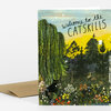 A folded greeting card with a colorful illustrated landscape cover that reads "welcome to the CATSKILLS," showing trees, flowers, a black cat, and small deer and birds.