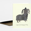 A folded greeting card with a pale yellow front showing a winking black dog illustration and the text "I am Winking at You."