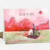A greeting card with the text "YOU ARE MY HOME." and an illustration of a small black tower-like house on a tiny island surrounded by pink trees and red hills.