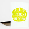 A folded greeting card with a bright yellow hand-drawn circle containing the words "I BELIEVE IN YOU" in white block letters.