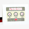 A greeting card with the text "My Love Goes to 11" above three illustrated knobs labeled "GAIN," "VOLUME," and "TREBLE," each with a heart-shaped pointer and a red heart at the bottom.