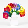 A colorful flower-shaped desk calendar arranged like a bouquet in a white vase, with visible month numbers and day grids on each petal and the number 2027 implied by the product context.