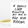 A folded white greeting card with bold handwritten-style black text that reads, "I REALLY Like Knowing you are in the next ROOM."
