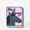 A die-cut sticker shaped like a book cover with the words "Black Beauty" in black script above a glittery dark horse illustration on a pink background.