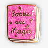 A pink glitter enamel pin shaped like a book, with the words "Books are Magic" and small star decorations on the cover.