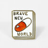 A rectangular enamel pin shaped like a book cover with the text "BRAVE NEW WORLD" and a glittery orange-and-white capsule illustration in the center.