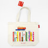 An ivory canvas tote bag with two handles printed with a colorful row of cookbook spines and the text "IDEAL BOOKSHELF" near the bottom.
