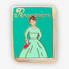 A rectangular enamel-style pin shaped like a book cover with the word "Persuasion" at the top and an illustrated woman in a pale dress holding a red heart-shaped object.