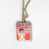 A gold-tone chain necklace with a book-shaped charm labeled "Pride and Prejudice" and illustrated with a woman in a white dress and a small heart icon.