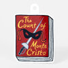 A sticker shaped like a stack of books, with a red book cover design reading “The Count of Monte Cristo” and featuring a black masquerade mask and a sword illustration.