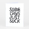 A small white zine or booklet with the hand-lettered cover text "SOME DAYS JUST SUCK" in bold black letters.