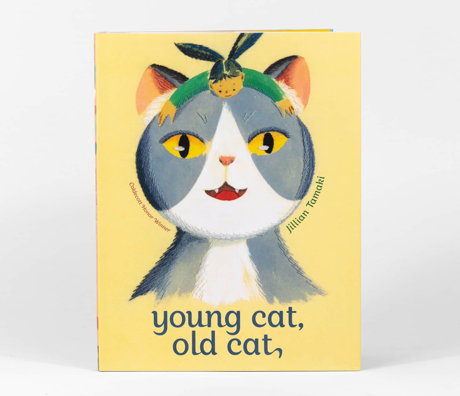 A paperback book cover with an illustrated gray and white cat wearing a green headband, the author name "Jillian Tamaki," the text "Caldecott Honor Winner," and the title "young cat, old cat,".