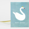 A folded greeting card with a white swan illustration, a small yellow crown, and the text "HAPPY BIRTHDAY" on a blue-green front, shown with a matching envelope partially behind it.