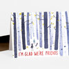 A folded greeting card shows a watercolor-style birch forest scene with two small figures and a dog, and the front reads "I'M GLAD WE'RE FRIENDS" in red lettering.