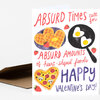 A greeting card with hand-lettered text reading “ABSURD TIMES call for ABSURD AMOUNTS of heart-shaped foods HAPPY VALENTINE'S DAY!” and illustrations of heart-shaped waffles, a heart-shaped fried egg in a pan, a heart-shaped pizza, and strawberries.