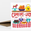 A greeting card with the text "COMFORT and JOY" and colorful illustrated holiday treats, including a teapot, cake, mug, and a red horse figurine.