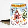 A greeting card with the text "COZY CHRISTMAS WISHES" above a winter illustration of a red house, decorated evergreen tree, bare trees, and several chickens in the snow.