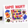 A folded greeting card with the hand-painted text “GAME NIGHT!” and colorful illustrations of a board game path, dice, cards, pretzels, and coffee cups.