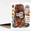 A folded greeting card with an illustration of three owls in a tree trunk and the text "LOVE YOU MOM" in red lettering.