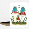 A greeting card featuring two green frogs sitting on red-and-white spotted mushrooms with the text "ME + YOU" above them.