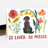 A folded greeting card featuring a black dog silhouette surrounded by colorful watercolor flowers and the red text "SO LOVED. SO MISSED."