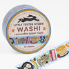 A roll of washi tape labeled "LITTLE TRUTHS STUDIO WASHI removable paper tape 10 meters" with a brunch-themed pattern showing pancakes, a fried egg, banana, newspaper, and other small illustrated food items.