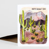 A folded greeting card with a watercolor desert scene of tall cacti and mountains and the text "HAPPY FATHER'S DAY" at the top.