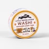A roll of washi tape labeled "LITTLE TRUTHS STUDIO," "WASHI," "removable paper tape," "MEET ME AT THE BOOKSTORE," and "10 meters," with small illustrated bookstore and outdoor scenes around the label.