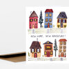 A folded greeting card with an illustration of six colorful houses and the text "NEW HOME, NEW ADVENTURE!" on the front.