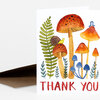 A folded thank you card with a watercolor illustration of orange and blue mushrooms, green fern fronds, and a snail, with the words "THANK YOU" printed in red at the bottom.
