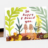 A folded greeting card with hand-painted woodland plants, acorns, and two morel mushrooms, with the text "so happy I found you."