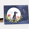 A greeting card featuring a black dog silhouette in front of a large white moon, surrounded by flowers and the handwritten text "so much love".