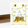 A folded birthday card with a watercolor-style illustration of sunflowers, a tiered cake on a tree stump, bunting, bees, and the text "Happiest of birthdays to you!" on the front.