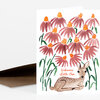 A folded greeting card with a watercolor illustration of pink coneflowers and a reclining fawn, with the text "Welcome Little One" on the front.