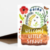 A greeting card with the text "WELCOME LITTLE SPROUT" and a colorful illustration of plants, flowers, insects, and mushrooms growing from a soil mound.