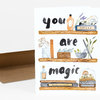 A folded greeting card shows watercolor shelves with bottles, books, herbs, mushrooms, and a skull, with the words "you are magic" across three lines.