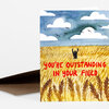 A folded greeting card with a front illustration of a wheat field under a cloudy sky and red text reading "YOU'RE OUTSTANDING IN YOUR FIELD."
